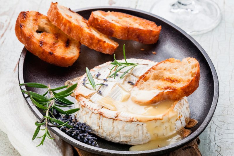 Baked Camembert cheese with toasted bread on cast-iron frying pan