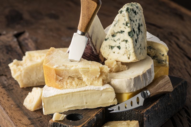 Assortment of different cheese types on wooden background. Cheese background.