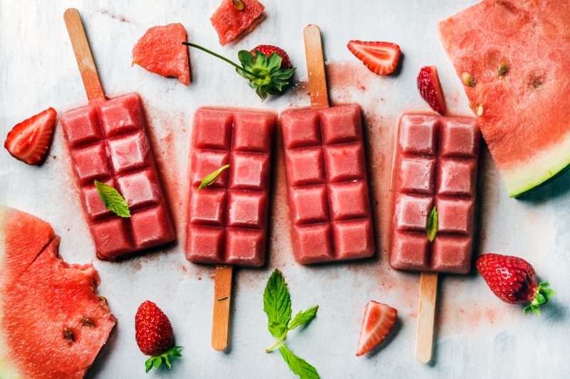 Strawberry watermelon ice cream popsicles with mint over steel tray background. Top view