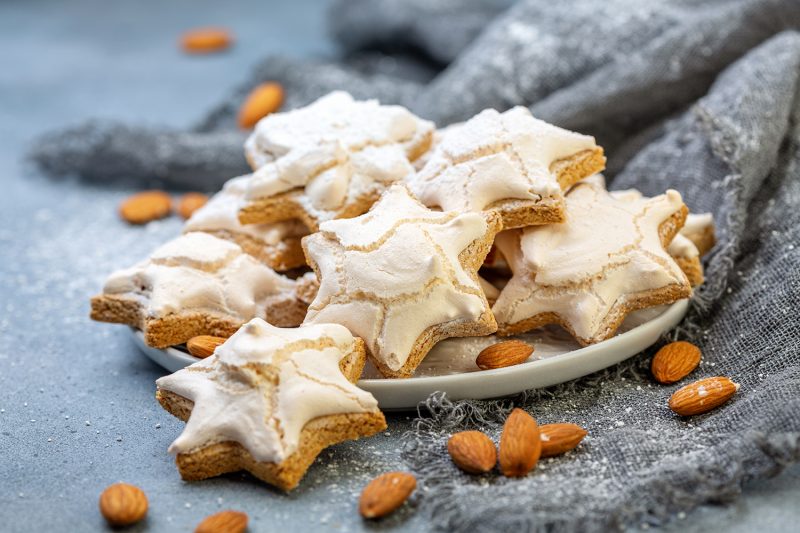 Plate of homemade German cinnamon cookies in the shape of a star on a gray concrete background, selective focus.