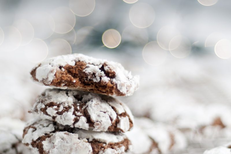 Chocolate crinkle cookies arranged on a baking tray with christmas lights in background.