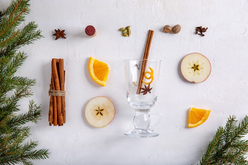 Ingredients for preparation of mulled wine on white background. Fruits - apple, orange; spice - clove, anise, nutmeg, cardamom, cinnamon Traditional hot drink in Christmas time. Top view.