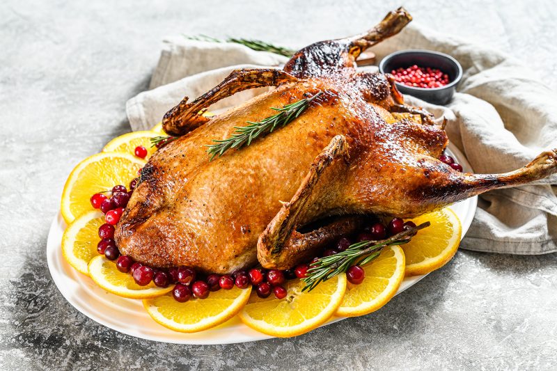 Baked chicken stuffed with oranges and rosmarina. Festive table. Gray background. Top view.