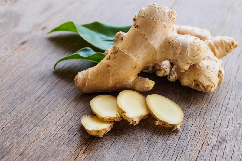 Ginger root slice with leaf and has a spicy taste Ginger root slice with leaf and has a spicy taste on wooden background