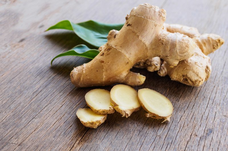 Ginger root slice with leaf and has a spicy taste on wooden background