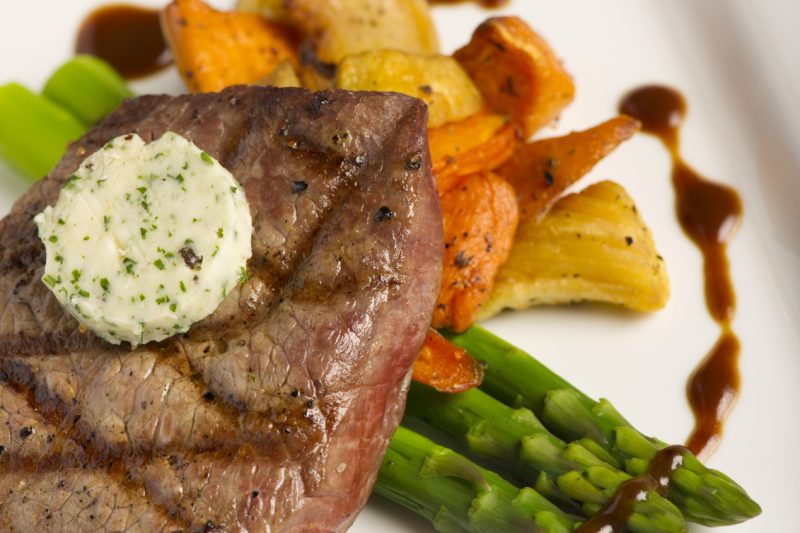 Gegrilltes Steak auf feinem Gemüse mit Kräuterbutter