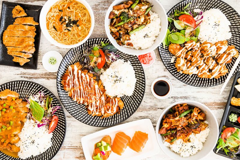 Traditional Japanese food - sushi, rolls, rice with shrimp and udon noodles with Katsu chicken on table.