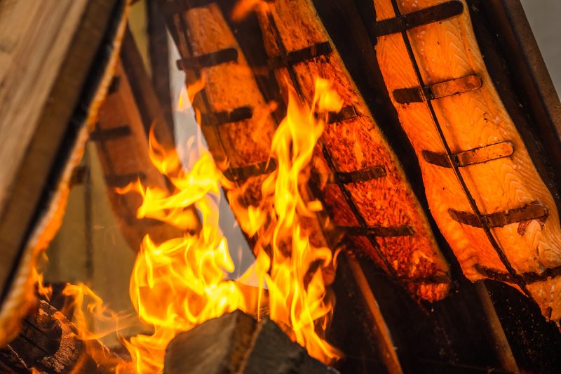 Flammlachs wird an Holzbrettern am Feuer gegart