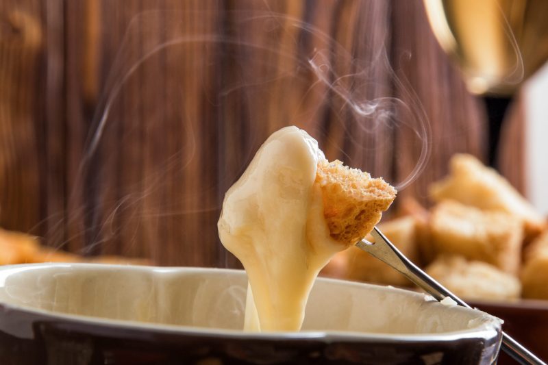 Käsefondue close up Brotwürfel aufgespießt auf einer Fondue-Gabel mit geschmolzenem Käse