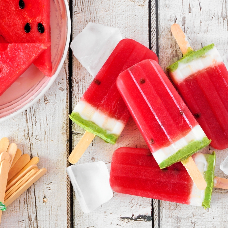 Group of homemade summer watermelon popsicles, top view over rustic white wood